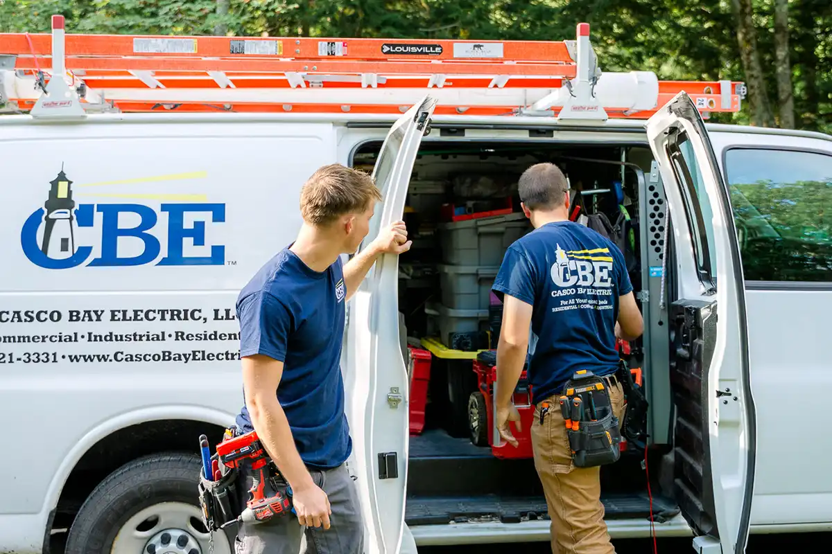 CBE electricians preparing with van doors open near trees