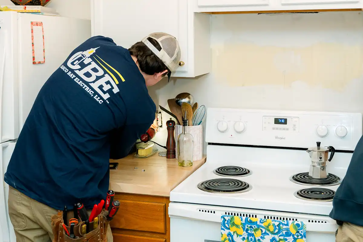 CBE electrician working on outlet in kitchen